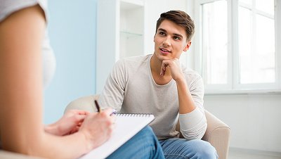 Мужчина сидит на стуле и разговаривает с врачом